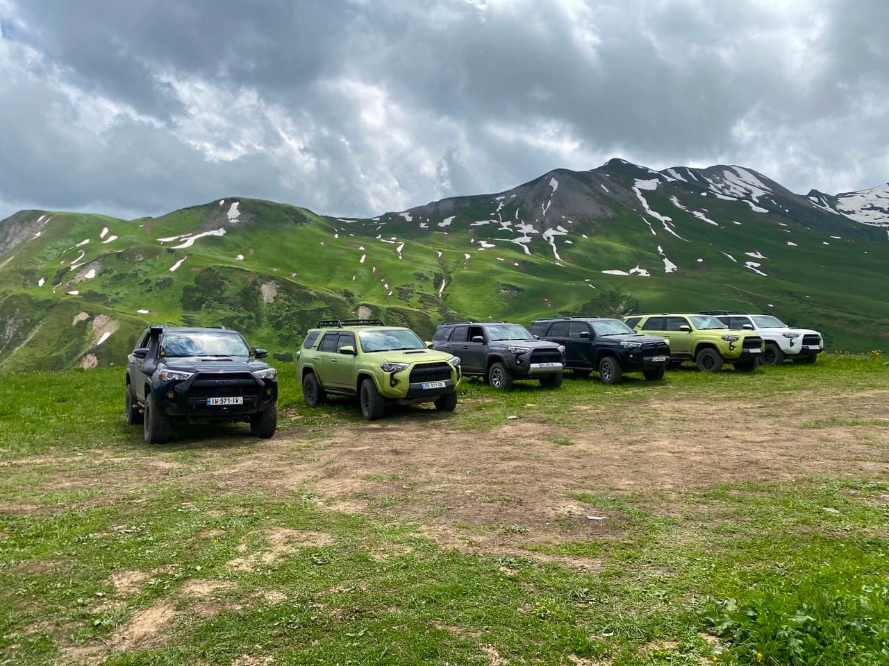 A row of Toyota 4Runners parked on a green mountain plateau in Georgia
